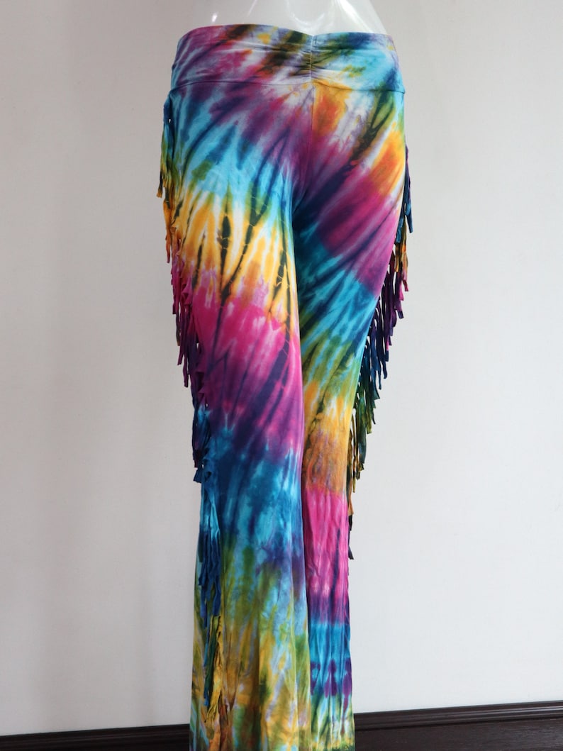 May include: Tie-dye pants with fringe detail. The pants are a mix of blue, purple, pink, yellow, and green.