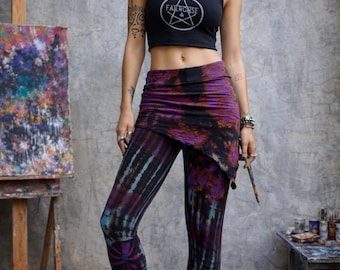 May include: A black crop top with a white pentagram graphic and the text "FAILRONSE" paired with purple and black tie-dye leggings featuring an attached wrap-style skirt overlay, worn with a black cap and black lace-up combat boots.