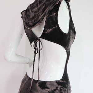 Puede incluir: Un mono con capucha de color marr&oacute;n y negro con estampado tie-dye, con la espalda recortada y un lazo en la parte posterior del cuello.
