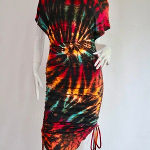 May include: A black tie-dye dress with a cowl neck and a gathered skirt. The dress has a swirling pattern of orange, red, blue, and green.