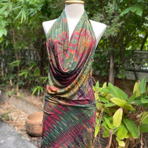 Op de afbeelding: Een halterjurk met een cowl-hals en een tie-dye-patroon in tinten groen, roze en oranje. De jurk is gemaakt van een zachte, rekbare stof en heeft een aansluitende pasvorm.