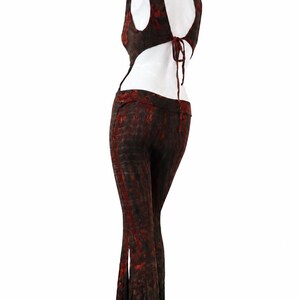 May include: A two-piece outfit featuring a sleeveless top with a high neck, an open back with tie closures, and matching flared pants. The garment is made of a dark brown fabric with a mottled, tie-dye style pattern in shades of deep red.