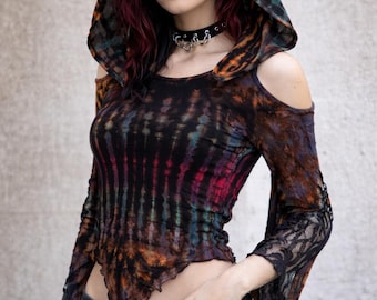 May include: A long-sleeve hooded top featuring a black, orange, and teal tie-dye pattern. The garment has cold-shoulder cutouts, flared sleeves with black lace trim, and an asymmetrical hemline. It is paired with black denim jeans.