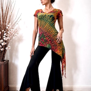 Może przedstawiać: Top tunika w stylu tie-dye z dekoltem w serek i krótkimi rękawami, z żywą mieszanką kolorów, w tym czerwonym, żółtym i zielonym. W połączeniu z czarnymi spodniami z rozszerzanymi nogawkami. Strój jest odpowiedni do noszenia na co dzień.