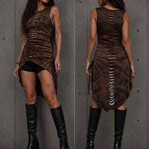 Pode incluir: Um vestido túnica sem mangas com padrão tie-dye castanho e preto, bainha assimétrica e uma fila vertical de cortes horizontais na frente e nas costas, combinado com calções pretos e botas pretas de cano alto com plataforma.
