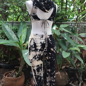 Puede incluir: Un mono de color negro y blanco tie-dye con una parte superior sin mangas y una capucha. La parte superior tiene un lazo en la parte posterior.