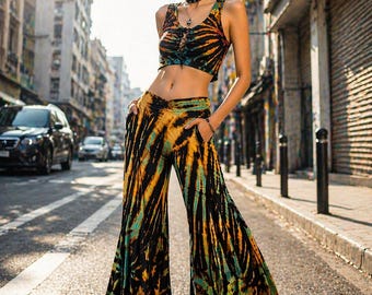 May include: A two-piece tie-dye outfit featuring a crop top and flared pants. The top has a lace-up front and the pants have pockets. The color scheme includes black, orange, and teal. The outfit is worn in an urban setting.