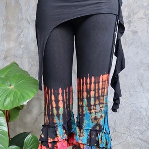 May include: Black cropped pants with a tie-dye pattern in shades of orange, blue, and pink. The pants have a ruffled hem and a wrap-around skirt.