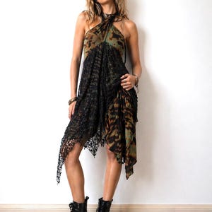 May include: A halter-neck dress with a tie-dye pattern in shades of green and brown, overlaid with a black lace skirt. The dress is paired with black combat boots. The model is standing on a zebra-print rug.