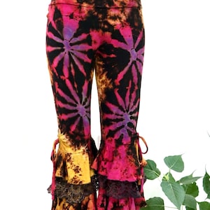 May include: Black tie-dye leggings with a pink, purple, and yellow color scheme. The leggings have a ruffled hem with black lace trim.