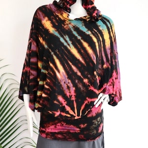 May include: A black hooded top with a tie-dye pattern in shades of pink, yellow, blue, and purple. The top has a loose fit and long sleeves.
