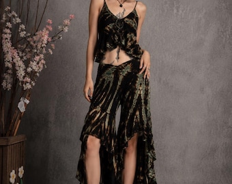 May include: A two-piece outfit consisting of a black and olive green tie-dye camisole top with thin straps and a matching high-low skirt with ruffled edges. The set is paired with black mid-calf boots, creating a coordinated ensemble.