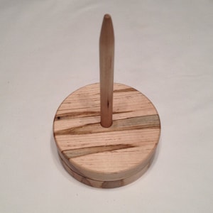 May include: Wooden yarn swift with a natural wood finish and a spindle.