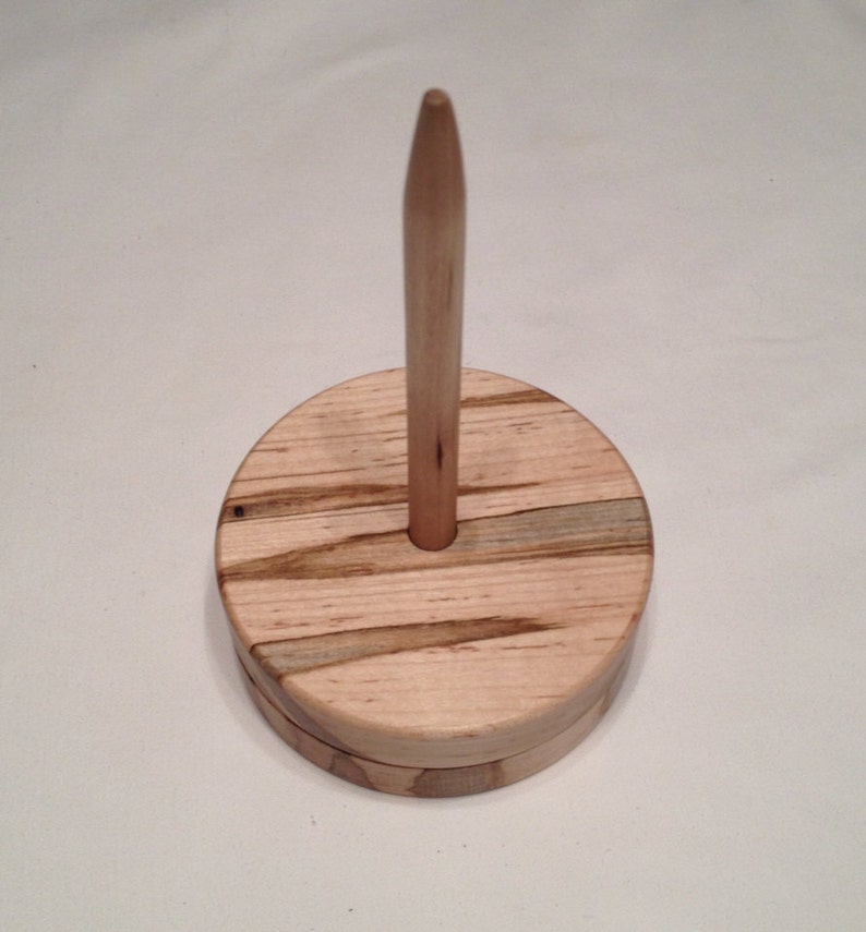 May include: Wooden yarn swift with a natural wood finish and a spindle.