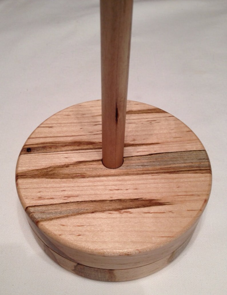 May include: A wooden yarn bowl with a natural wood finish and a round base. The bowl has a center hole for a spindle.