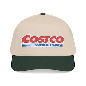 May include: A beige baseball cap with a dark green brim and a dark green button on top. The cap features the red and blue Costco Wholesale logo embroidered on the front.