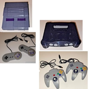 May include: A collection of retro-style gaming hardware including a light grey console with purple accents, a dark blue console, two grey rectangular controllers with black cords, and two grey trident-shaped controllers with black cords and USB connectors.