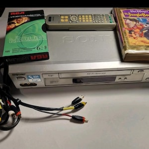 May include: A silver Sony Hi-Fi Stereo VCR with a grey remote control, a black RCA 6-hour VHS tape, a Walt Disney Masterpiece The Jungle Book VHS tape, and a set of black RCA cables with yellow, white, and red connectors for audio and video.