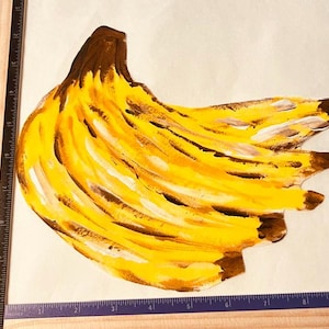 Peut inclure: Une illustration peinte à la main d'un régime de bananes en jaune, marron et blanc, placée à côté d'une règle indiquant une hauteur d'environ 25,4 cm et une largeur d'environ 25,4 cm pour l'œuvre d'art.