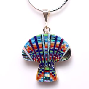 Könnte beinhalten: Eine farbenfrohe Anhänger-Halskette mit Mosaikdesign. Der pilzförmige Anhänger zeigt verschiedene Farben wie Blau, Rot, Orange und Grün. Die Halskette hat eine silberne Kette.