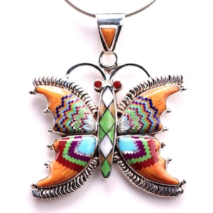 May include: A sterling silver butterfly pendant featuring intricate inlay work with orange, green, white, blue, and purple stones. The butterfly body is composed of diamond-shaped segments, and the wings display detailed geometric patterns.