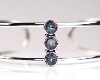 Peut inclure: Un bracelet jonc en argent avec trois pierres précieuses violettes irisées disposées verticalement.