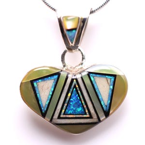 May include: Heart-shaped pendant necklace with a silver chain. The pendant features a heart design with a green, white, and blue geometric pattern. The pendant is approximately 1.5 inches wide.