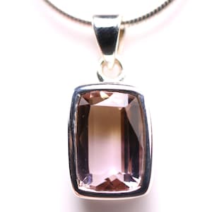 May include: A silver pendant necklace featuring a rectangular, faceted gemstone with a gradient of light pink to brown hues. The pendant is set in a silver bezel and hangs from a delicate silver chain.