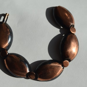 May include: A copper bracelet with oval-shaped links. The links are a dark copper color with a shiny finish.