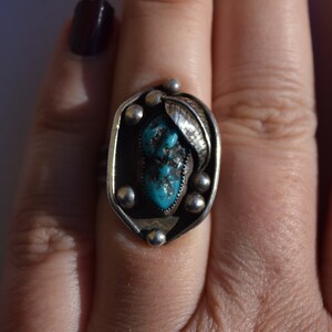 Puede incluir: Un anillo de plata con una piedra turquesa engastada en un dise&ntilde;o de hoja.