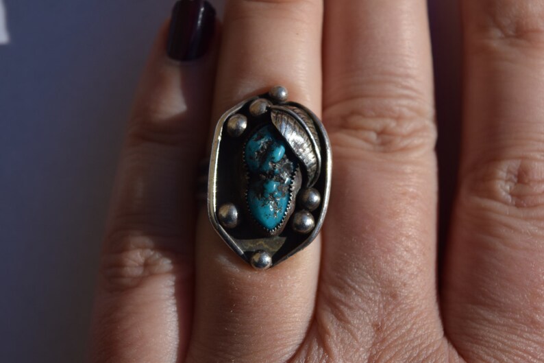 Puede incluir: Un anillo de plata con una piedra turquesa engastada en un dise&ntilde;o de hoja.