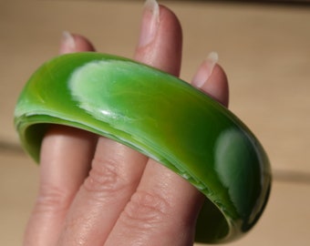 May include: A green and white bangle bracelet with a swirl pattern. The bracelet is made of a smooth, glossy material.