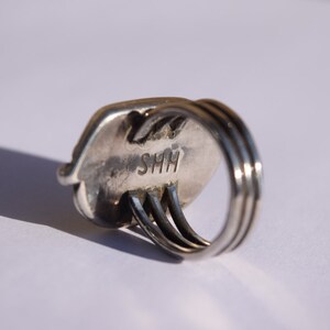 Puede incluir: Anillo de plata con una banda ovalada texturizada y un engaste de triple banda. El anillo est&aacute; marcado con "SHH" en el interior.