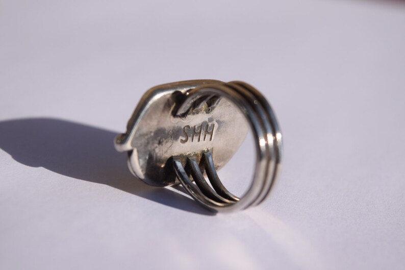 Puede incluir: Anillo de plata con una banda ovalada texturizada y un engaste de triple banda. El anillo est&aacute; marcado con "SHH" en el interior.