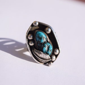 Puede incluir: Un anillo de plata con una piedra turquesa engastada en un dise&ntilde;o de hoja.