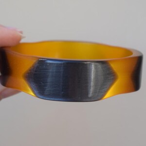 May include: A yellow and black plastic bangle bracelet with a geometric pattern.