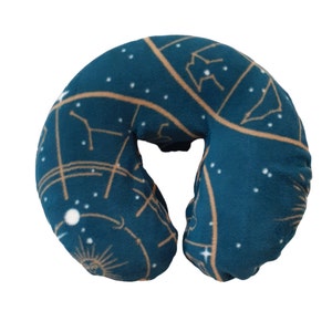 May include: A teal blue travel neck pillow with a gold constellation pattern. The pillow is made of soft fleece and is designed to provide support for the neck and head.