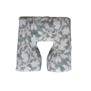 May include: A U-shaped neck pillow with a floral pattern in shades of green and cream. The pillow is made of a soft, plush material, ideal for travel or relaxation. The design features stylized leaves and vines.