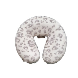 May include: A white and gray leopard print neck pillow for massage therapy.