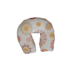 May include: A white travel pillow with a cheerful sun pattern. The pillow is shaped like a horseshoe and has a soft, plush fabric.