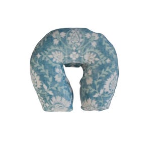 May include: A blue and white patterned neck pillow for massage therapy. The pillow is shaped like a horseshoe and has a soft, plush fabric.