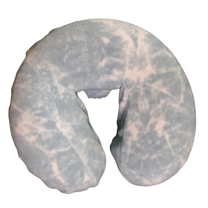 May include: A light blue and white patterned massage table face cradle cushion. The cushion has a U-shape with a central opening for the face. The soft, plush material is designed for comfort and support during spa treatments.