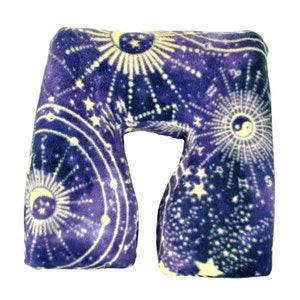 May include: A purple and white travel pillow with a celestial pattern featuring stars, moons, and suns. The pillow is shaped like a U and is designed to support the neck and head.