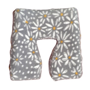 May include: A gray travel pillow with a white daisy pattern. The pillow has a U-shape and is made of soft, plush fabric.