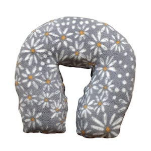 May include: A gray u-shaped neck pillow with a white daisy pattern. The daisies have yellow centers.