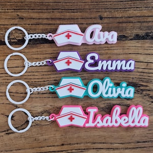 May include: Four keychains with nurse hat designs and names: Ava, Emma, Olivia, and Isabella. Each keychain features a white ring, chain, and a colorful nurse hat with a red cross. The names are in various colors, including pink, purple, and teal.