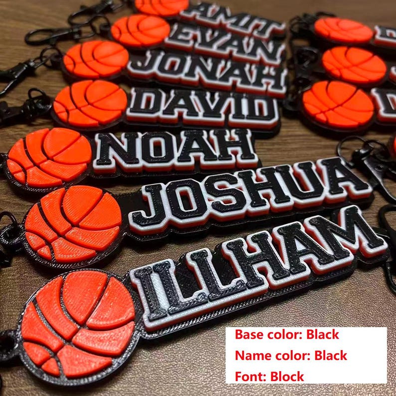 May include: Basketball-themed keychains with personalized names in black and white block lettering. Each keychain features a 3D-printed orange basketball. The base color is black, and the name color is black.