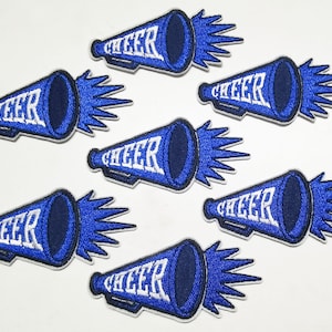 May include: Eight embroidered patches featuring a blue megaphone design with the word "CHEER" in white. The megaphones have a blue body and white outline, with blue bursts at the back. The patches are suitable for clothing or accessories.