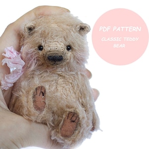 May include: A PDF pattern for a classic teddy bear. The pattern is for a small teddy bear with a light brown fur and a pink ribbon.