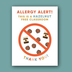 Puede incluir: Un letrero blanco con el texto "ALLERGY ALERT! THIS IS A HAZELNUT FREE CLASSROOM" en naranja, verde azulado y amarillo. Un círculo rojo con una línea que lo atraviesa contiene ilustraciones de avellanas. El texto "THANK YOU!" está en la parte inferior.